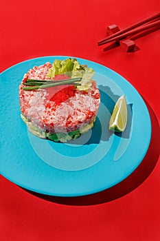 Tartar with tuna and caviar with lime at blue pastel color plate at blue at red background with sunlight and shadows, minimalism,