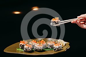 Tartaro Roll in Chinese chopsticks in hand over the dish on the table