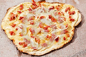 Tarte flambee with bacon and onions, top view. Tasty pizza on the table.