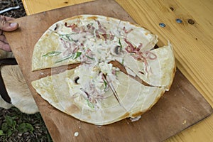 Tarte flambee while preparing with bacon, onions and cream fresh,