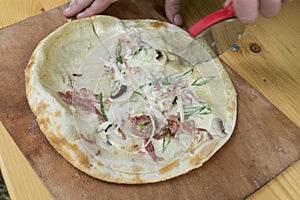 Tarte flambee while preparing with bacon, onions and cream fresh,