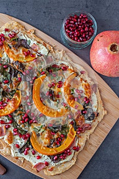 Tarte flambee with pumpkin, cheese, kale and pomegranate