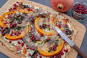 Tarte flambee with pumpkin, cheese, kale and pomegranate