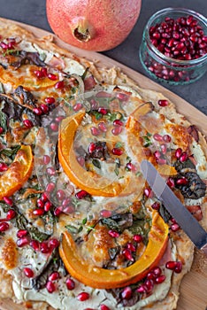 Tarte flambee with pumpkin, cheese, kale and pomegranate