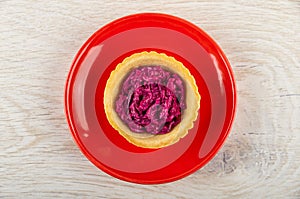 Tartlet with beetroot salad in red saucer on table. Top view