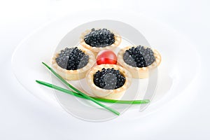 Tartlet with black caviar on a white platter