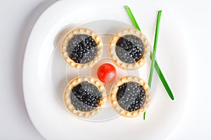 Tartlet with black caviar on a white platter photo
