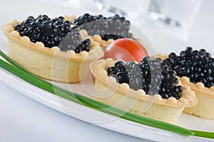 Tartlet with black caviar on a white platter