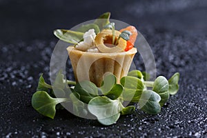 Tartlet with salmon and curd cheese with micro-green on a dark background.