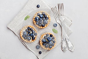 Tartlets with blueberries, bilberry, ricotta and honey syrup on vintage background from above. Delicious dessert. Flat lay styling
