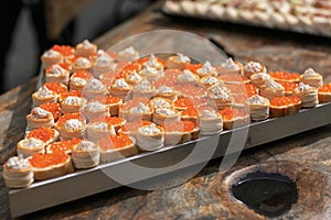 tartlets with butter and red caviar on a black wooden table