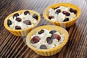 Tartlets with cottage cheese and raisin on wooden table