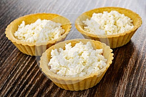 Tartlets with cottage cheese on wooden table