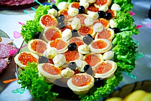 Tartlets on lettuce leaves with red caviar close-up. Buffet table with seafood, appetizer.