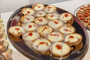 Tartlets with red caviar on a dish on the buffet table. Festive table setting at events. Close-up