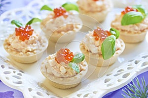 Tartlets with seafood salad, red caviar and basil