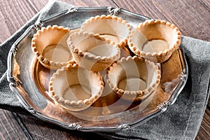 Tartlets on silver vintage plate with linen napkin on wooden table