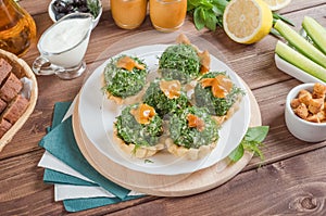 Tartlets stuffed with beef, champignons and potatoes with greens on a white plate on a dark wooden background