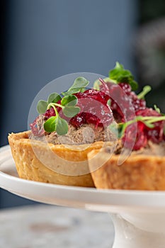 Tartlets stuffed with codfish liver, codfish caviar and microgreens. Traditional cold portioned appetizer in a pastry