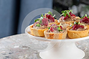 Tartlets stuffed with codfish liver, codfish caviar and microgreens. Traditional cold portioned appetizer in a pastry