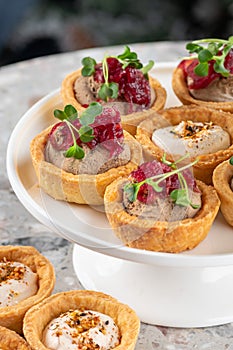 Tartlets stuffed with codfish liver, codfish caviar and microgreens. Traditional cold portioned appetizer in a pastry