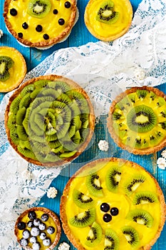 Tartlets, tartas from custard, kiwi and black currant of different sizes photo