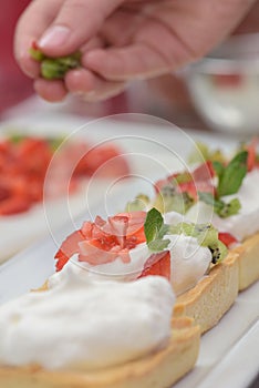 Tarts with whipped cream and strawberries and mint leaves