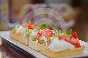 Tarts with whipped cream and strawberries and mint leaves