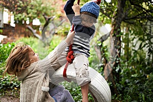 Tarzan and Jane. two cute kids playing on a tire swing in their garden.