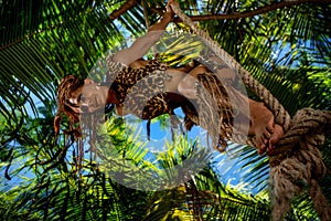 Tarzan wearing in leopard fur swinging on a rope in jungle