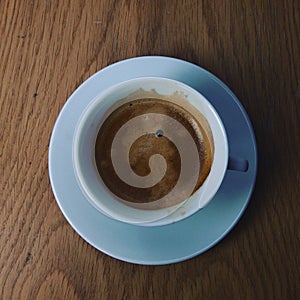 tasse blanche de cafÃ© avec soucoupe sur une table en bois, vue aÃ©rienne