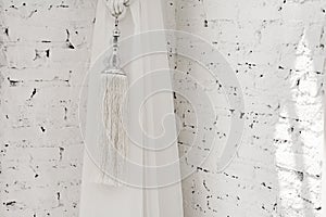 Tassels of curtain on white brick background