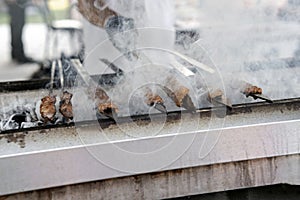 Taste of Adana kebabs with smokes on a bbq in a food festival, close up