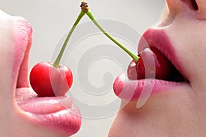 Taste. Closeup of women mouths kissing. Two beautiful sexy lesbians in love. Girls friends. Fruit lips. Cherry in female