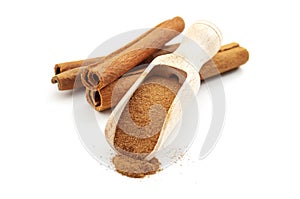 Taste enhancing and flavour spice concept with wooden scoop with fine powder and cinnamon sticks isolated on white background