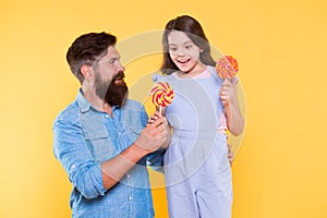 Taste the rainbow. Family of father and daughter eat candies. Happy family yellow background. Bearded man entertain