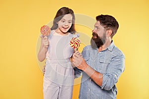 Taste the rainbow. Family of father and daughter eat candies. Happy family yellow background. Bearded man entertain