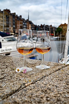 Tasting of apple calvados drink in old Honfleur harbour with boats and old houses on background, Normandy, France