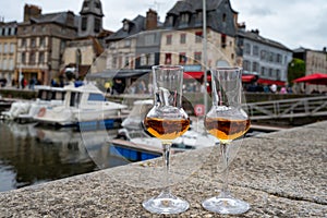 Tasting of apple calvados drink in old Honfleur harbour with boats and old houses on background, Normandy, France