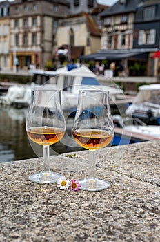 Tasting of apple calvados drink in old Honfleur harbour with boats and old houses on background, Normandy, France