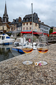 Tasting of apple calvados drink in old Honfleur harbour with boats and old houses on background, Normandy, France