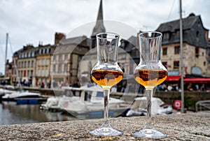 Tasting of apple calvados drink in old Honfleur harbour with boats and old houses on background, Normandy, France