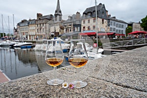 Tasting of apple calvados drink in old Honfleur harbour with boats and old houses on background, Normandy, France