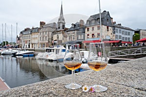 Tasting of apple calvados drink in old Honfleur harbour with boats and old houses on background, Normandy, France