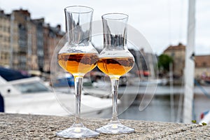 Tasting of apple calvados drink in old Honfleur harbour with boats and old houses on background, Normandy, France