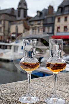 Tasting of apple calvados drink in old Honfleur harbour with boats and old houses on background, Normandy, France