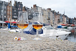 Tasting of apple calvados drink in old Honfleur harbour with boats and old houses on background, Normandy, France