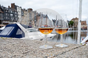 Tasting of apple calvados drink in old Honfleur harbour with boats and old houses on background, Normandy, France