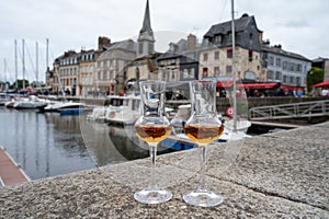 Tasting of apple calvados drink in old Honfleur harbour with boats and old houses on background, Normandy, France