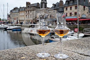 Tasting of apple calvados drink in old Honfleur harbour with boats and old houses on background, Normandy, France